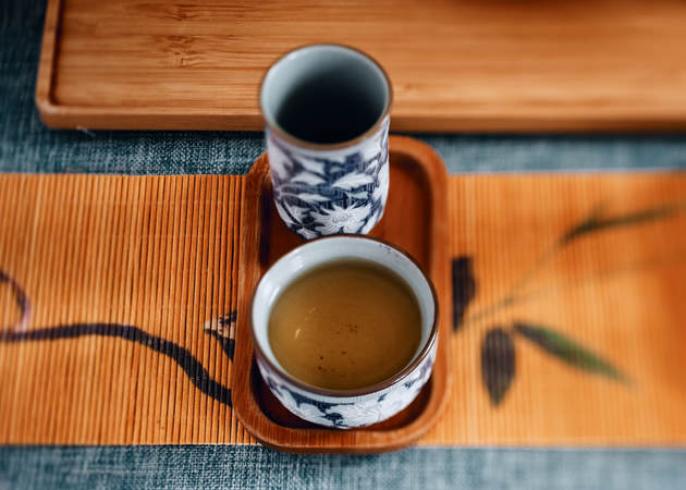 Китайское традиционное чаепитие, заваренный чай улун в чашке на бамбуковом подносе